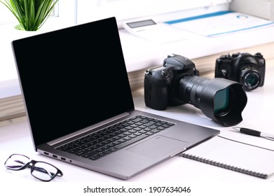 Online classes of shooting with a camera. On the table are a computer and a camera with a lens. Online training for photographers