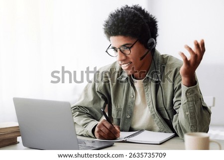 Online communication and web based learning. Positive black teenager speaking to his college tutor on laptop from home