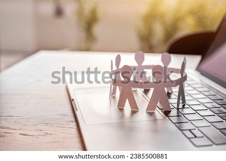 online community concept, group circle of paper humans standing together on computer keyboard