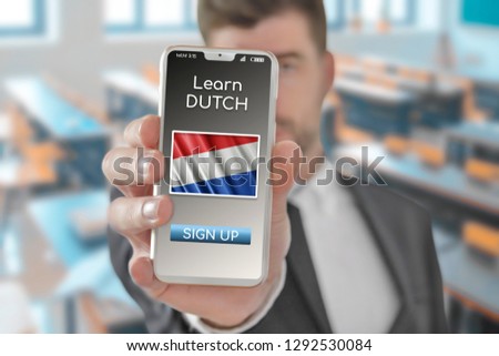 Online concept learn Dutch language with a person showing e-learning app on mobile phone with the flag of Netherlands