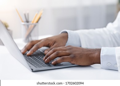 Online Consultation. Close Up Of Black Doctor Hands Typing On Laptop, Office Interior