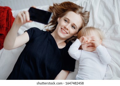 Online Consultation With Doctor On Video Communication Via Phone For Young Mother With Child, Baby Cries And Rubs Eyes.