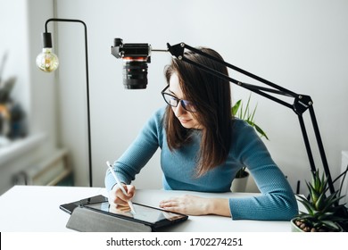 Online content creator vlogger. A young women blogger with glasses removes the content for the blog, training courses. The concept of online learning to draw on the tablet.