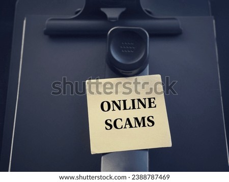 Online crime issues concept. ONLINE SCAMS written on a paper. With blurred style background.