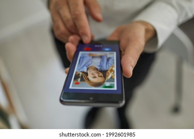 Online dating concept. Closeup man pressing red heart button and giving a like to attractive young woman's photo on dating website or mobile phone app. Hands holding cellphone in close up