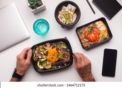 Online Delivery. Man Eating Healthy Food During Lunch Time In Office, Cellphone With Blank Screen