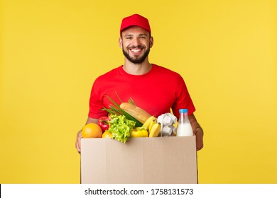 Online Delivery, Shopping And Food Order Concept. Nice Delivery Guy, Courier In Red Uniform Company, Bring Grocery Order In Box To Client, Smilign Friendly, Standing Yellow Background