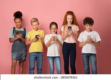 Online education concept. Adorable multinational schoolkids stuck in smartphones on pink background - Powered by Shutterstock