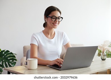 Online education concept. Young beautiful brunette woman wearing eyeglasses taking part in a group video call. Portrait of female college student studying at home. Close up, copy space, background.