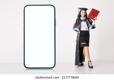 Online education, e-learning concept with big blank cellphone with white screen for your mockup and university graduate indian race woman wearing academic regalia and holding red diploma. - Shutterstock ID 2177778069