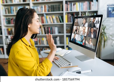 Online Education. A Female Student Learning Online At Home, She Waving Hand To Other Students Or Colleagues On Computer Monitor In Video Conference And Smiling