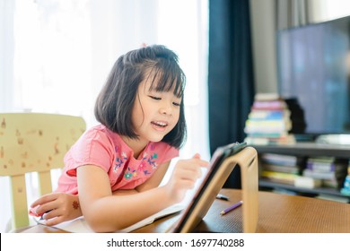 Online education, Online learning.Little asian girl studying homework math during her online lesson at home with tablet, Social distance, Quarantine, self isolation, Online education concept.Covid-19.