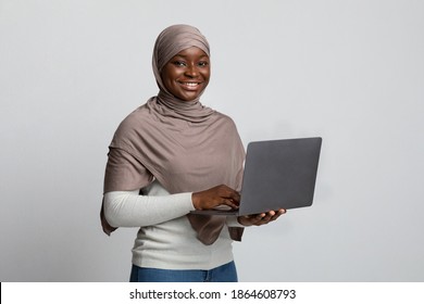 Online Education. Portrait Of Smiling Black Muslim Lady In Headscarf Holding Laptop, Enjoying Distance Learning, Positive African Islamic Woman Posing With Computer Ocer Light Studio Backgrond