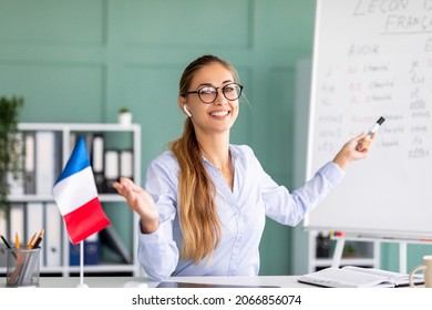 Online Foreign Languages Tutoring. Happy Teacher Giving French Class, Pointing At Blackboard With Basic Grammar Rules. Young College Professor Explaining New Material Tenses To Students