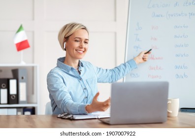 Online foreign languages tutoring. Joyful female teacher giving Italian class, pointing at blackboard with basic grammar rules. Experienced college professor explaining new material to students - Powered by Shutterstock