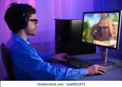 Online Gaming. Gamer Guy Playing Games Sitting At Desktop PC At Home At Night. Selective Focus, Low Light