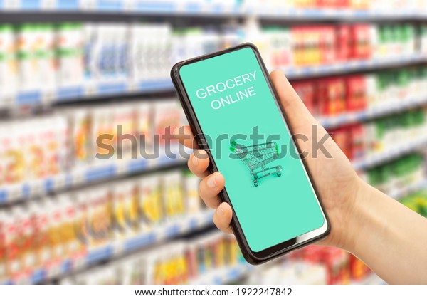 Online grocery delivery app in a mobile phone. Food\
market service in smartphone. Grocery delivery background concept.\
Shopping cart.