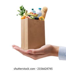 Online Grocery Shopping And Home Delivery Service: Tiny Grocery Bag With Food On A Hand On White Background