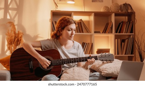 Online guitar class. Virtual music. Talented musician woman learning playing string instrument on laptop at home living room interior with free space. - Powered by Shutterstock