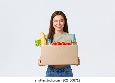 Online Home Delivery, Internet Orders And Grocery Shopping Concept. Smiling Satisfied Female Customer Receive Box With Groceries From Courier, Standing White Background