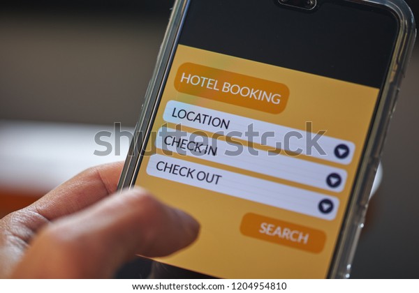 Online hotel booking and online travel\
concept. Male hands using smartphone for holiday vacation deal on\
mobile reservation app. Front view & close up. All screen\
graphics are made up with own\
design
