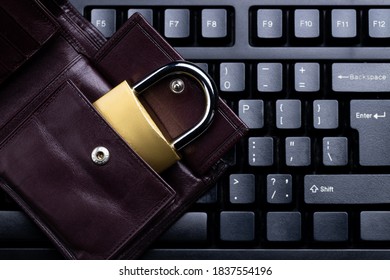 Online Investing Privacy Concept. Brown Leather Wallet And Golden Padlock On A Black Keyboard. Above View. Studio Shot.