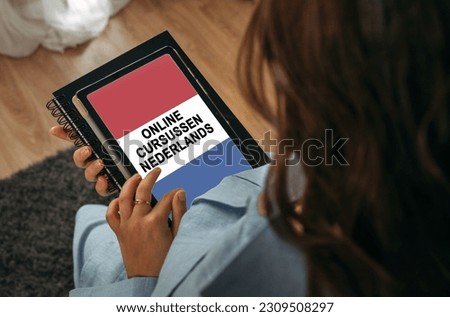 Online learning concept. A woman holds a tablet in her hands on the screen of which it is written - Online Dutch courses. The inscription is in Dutch.