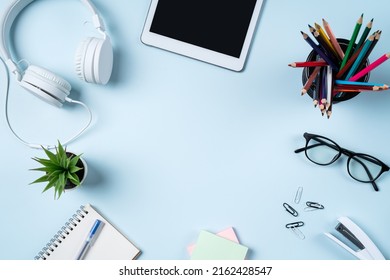 Online learning design concept. Top view of student table with tablet, headphone and stationeries on blue table background. - Powered by Shutterstock