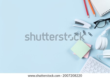 Online learning design concept. Top view of student table with computer, headphone and stationeries on blue table background.