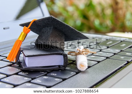 online learning or e-learning and online graduate certificate program concept : Black graduation cap, diploma on a laptop computer keyboard, depicts distant learning can be done via cyber / internet