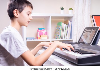 Online Learning, Remote Education. Boy Watching Video Tutorial At Tablet Computer, Playing Digital Piano And Singing At Home