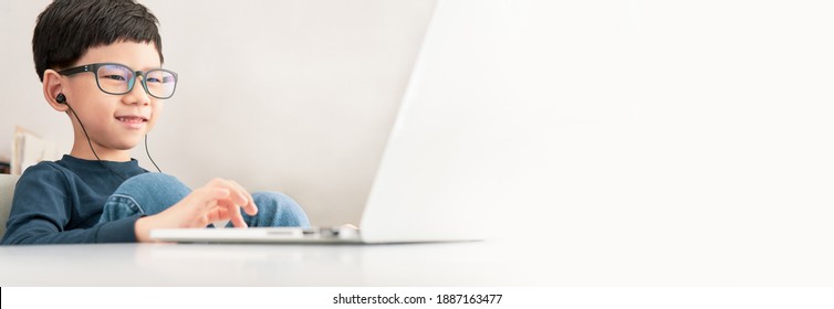 Online Learning Study From Home, Cute And Happy Asian Little Boy Click Touchpad On Computer Notebook To Study Online Lessons And Gamification At Home Due To Covid-19 Pandemic And School Break. Banner.