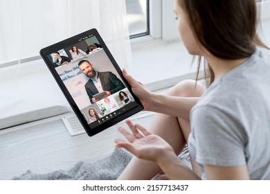 Online learning. Webinar class. Remote education. Relaxed female students watching male business coach virtual presentation on tablet screen at home.