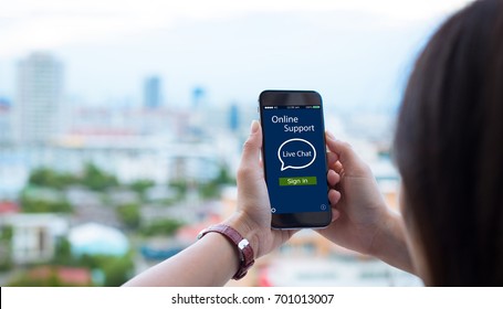 Online Live chat support concept.close-up of female hands holding mobile phone on blurred urban city as background