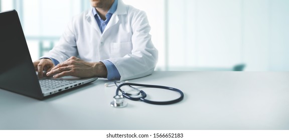 Online Medical Consultation - Doctor Working On Laptop Computer In Clinic Office. Copy Space