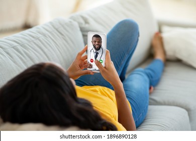 Online Medical Consultation. Woman Having Video Chat With Male Therapist On Smartphone, Unrecognizable Lady Talking With African American Doctor While Lying On Couch At Home, Creative Collage - Powered by Shutterstock