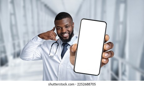 Online Medical Support. Black Doctor Holding Blank Smartphone And Showing Call Me Gesture While Standing In Clinic Hall, Smiling Male Physician Advertising Modern App Or Website, Collage, Mockup - Powered by Shutterstock