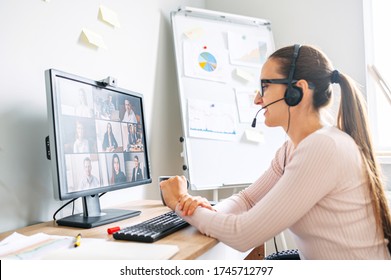 Online meeting, webinars. Young confident woman is using headset for video communication with coworkers, employees. Woman in glasses sits at the desk and talks online with many people together - Powered by Shutterstock