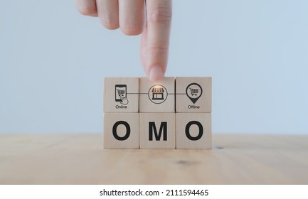 Online merge offline (OMO) concept. Borderless marketing channel conbination strategy creating new opportunities, sales increasing. Hand puts wooden cubes with combination of online and offline icon. - Shutterstock ID 2111594465
