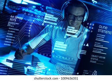 Online mode. Cheerful programmer coding and makiong notes while working late at night