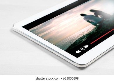 Online Movie Stream With Mobile Device. Close Up To White Tablet On Wooden Table With Imaginary Video Player And Film Streaming Service.