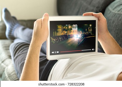 Online movie stream with mobile device. Man watching film on tablet with imaginary video player service. - Shutterstock ID 728322208