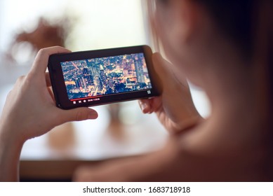 Online movie stream with smartphone. Woman watching film on mobile phone with imaginary video player service. - Powered by Shutterstock