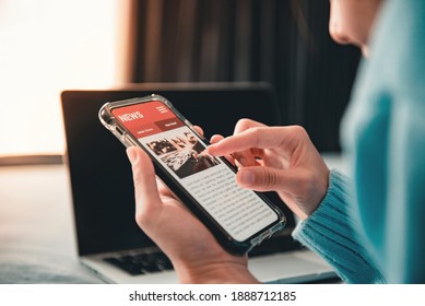 Online news on a smartphone. Mockup website. Woman reading news or articles in a mobile phone screen application at home. Newspaper and portal on internet. - Shutterstock ID 1888712185