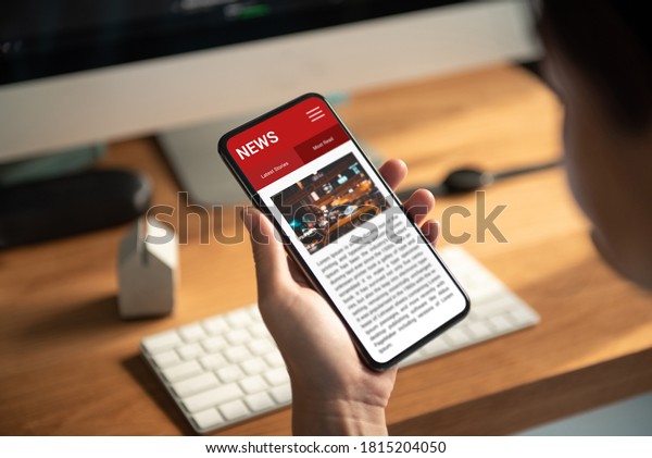 Online news on a smartphone.\
Mockup website. Woman reading news or articles in a mobile phone\
screen application at home. Newspaper and portal on\
internet.