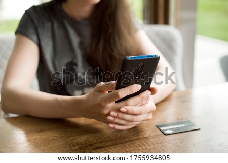 Online payment. Female hands holding phone for online shopping over the desk. Indoor close-up. Online shopping concept