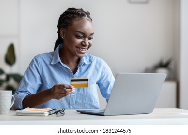 Online Payment. Smiling Black Businesswoman Using Laptop And Credit Card In Office, Paying Bills In Internet, Making Shopping, Checking Account Balance, Sitting At Desk With Computer, Free Space