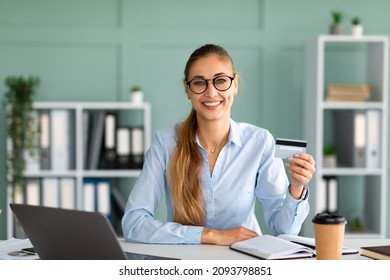 Online Payment. Smiling Young Businesswoman Using Laptop And Credit Card, Sitting On Workplace And Paying Bills In Internet, Making Shopping, Checking Account Balance