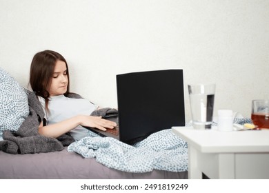 Online pharmacy, young sick woman orders medicines on a laptop via the Internet, patient at home using laptop for pharmaceutical needs. - Powered by Shutterstock