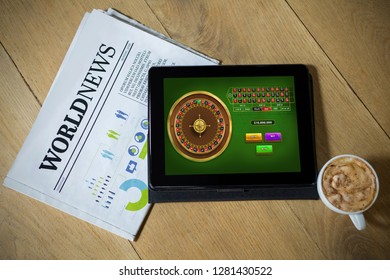 Online Roulette Game  Against Digital Tablet With Coffee And Newspaper On Table